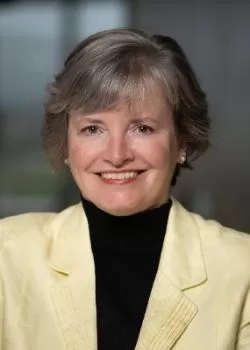 Image of Lisa Browne wearing a black turtle neck and a pale yellow jacket.